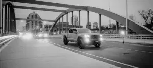 Truck navigating urban road at dusk, featuring performance tires and striking arch bridge backdrop.